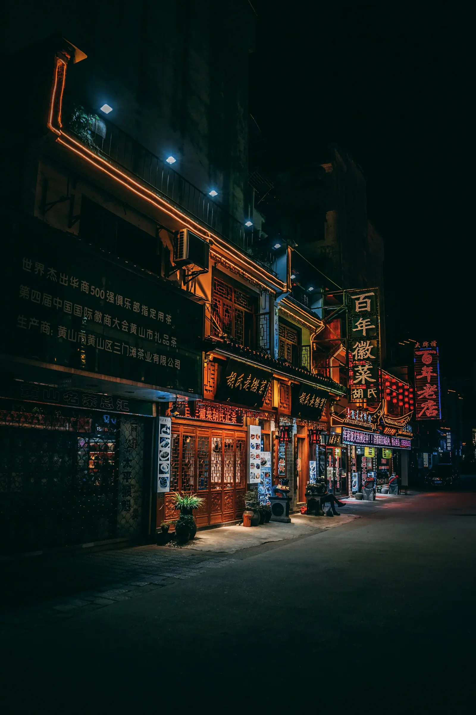 夜里亮着灯的旧式店铺,招牌的红光落在路面上