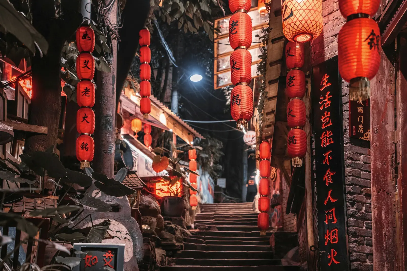 一条挂满红灯笼的石阶老巷,两侧是木门面的店铺