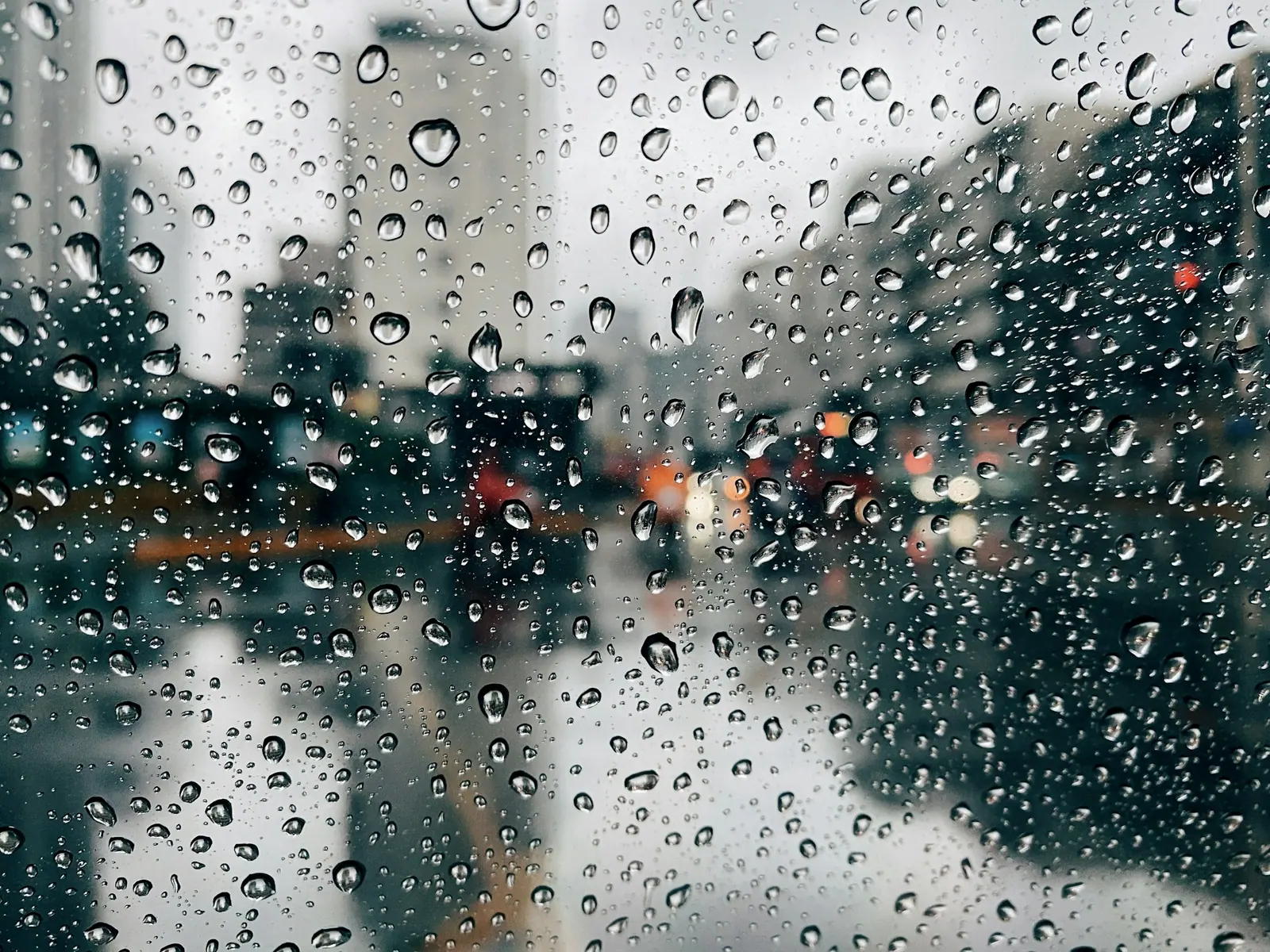 挂满水珠的车窗,窗外的路灯和车灯被雨揉成一团光