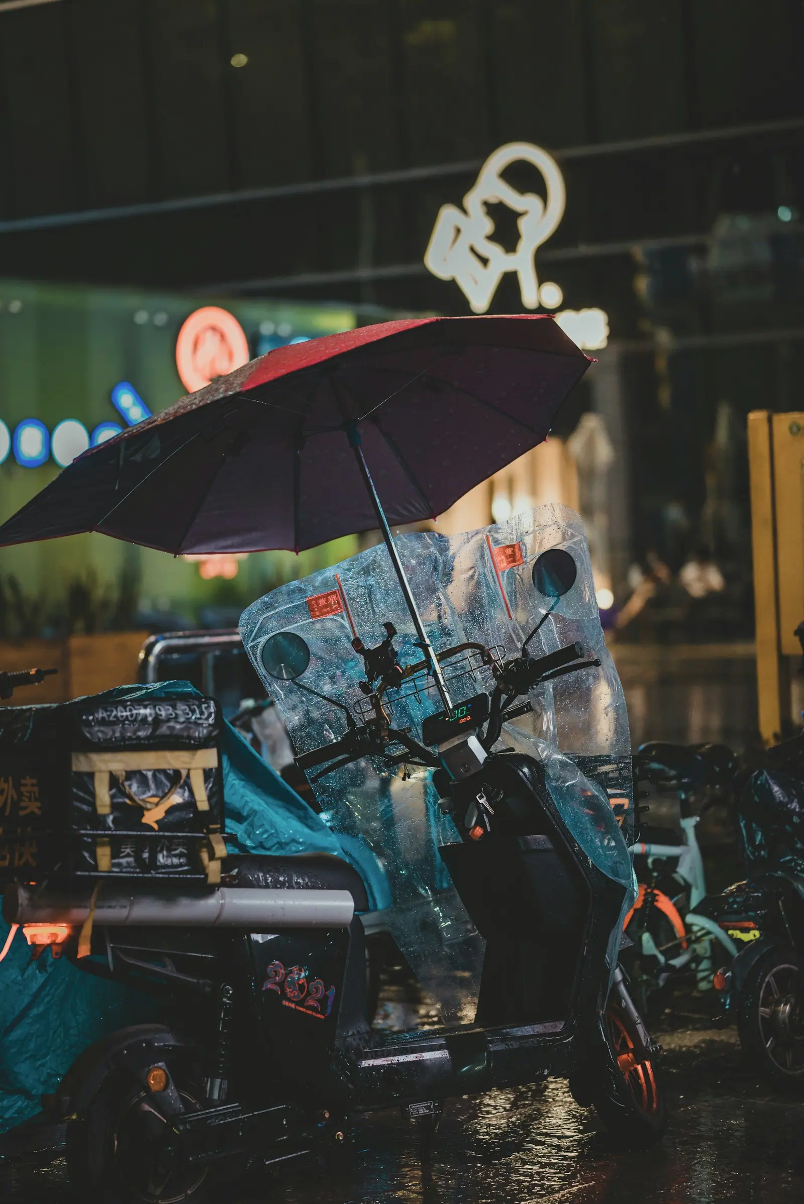 一辆电动车停在雨里,车上撑着一把伞