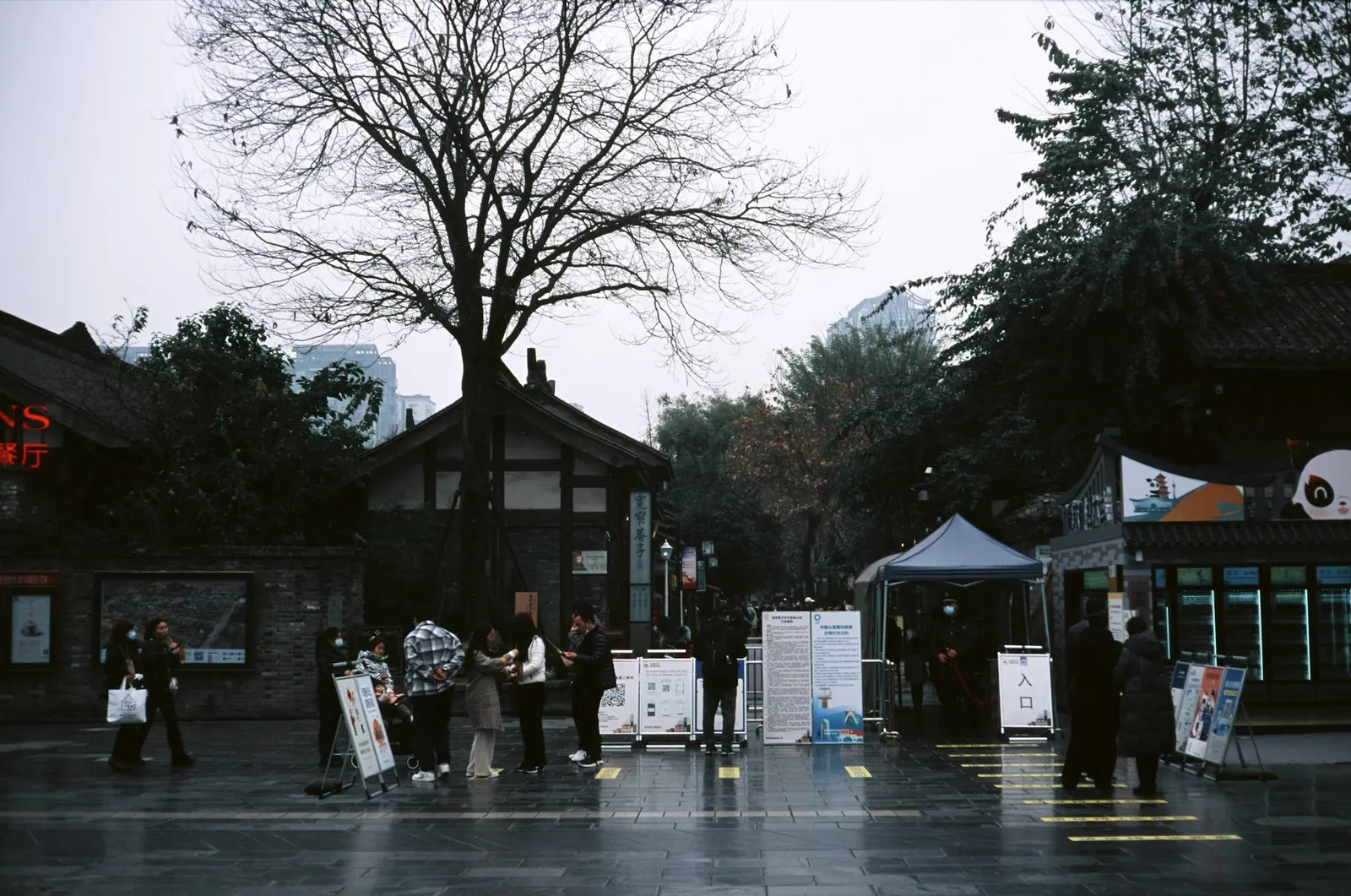 雨中的老街口,几个撑伞的人站在湿漉漉的地面上
