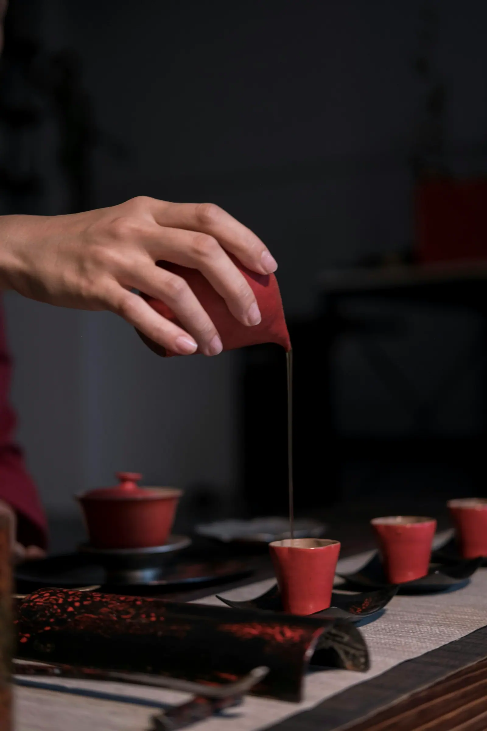 一只手把茶倒进红色的小杯里